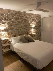 a bedroom with a bed with a stone wall at La casa de la raval de l’Albagés in Albagés