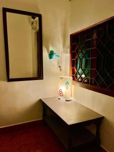 a bathroom with a table with a lamp and a mirror at La Ruelle Guest House in Puducherry