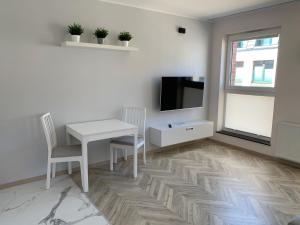 a living room with a white table and a tv at Olin Apartament B - Gdańsk Angielska Grobla in Gdańsk