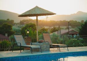 two chairs and an umbrella next to a swimming pool at Traditional house Alexis Coco with pool and fire place in Tríkorfon