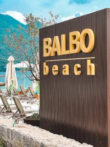 un cartello per un hotel con sedie e spiaggia di Apartments Balbo a Bijela