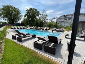 a swimming pool with lounge chairs next to a building at 25h SPA-Residenz BEST SLEEP privat Garden & POOLs in Neusiedl am See