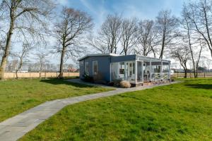 een blauw tiny house in een grasveld bij Eureka 75 Sint Maartenszee in Sint Maartensvlotbrug