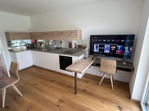 a kitchen with a desk and a large screen tv at 25h SPA-Residenz BEST SLEEP privat Garden & POOLs in Neusiedl am See
