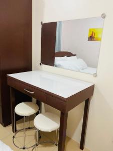 een badkamer met een wastafel met een spiegel en 2 krukken bij 8 Spatial Condominium in Davao City