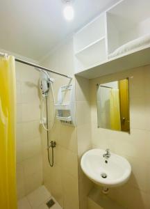 een badkamer met een wastafel en een douche met een spiegel bij 8 Spatial Condominium in Davao City
