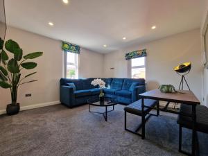 a living room with a blue couch and a table at DYSA Clifton Apartments in Lytham St Annes