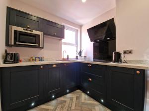 a kitchen with black cabinets and a microwave at DYSA Clifton Apartments in Lytham St Annes