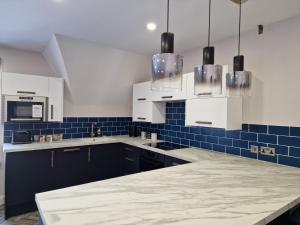 una cocina con armarios blancos y azulejos azules en DYSA Clifton Apartments, en Lytham St Annes