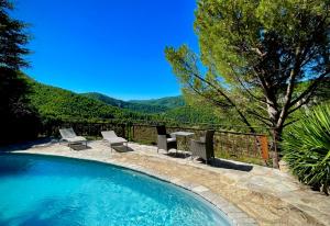 a swimming pool with chairs and a table with mountains in the background at Le Colombier Saint-Véran in La Roque-Sainte-Marguerite