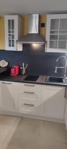 a kitchen with white cabinets and a sink at Le gîte des Pierres Dorées in Marcilly-dʼAzergues