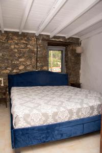 a blue bed in a room with a brick wall at Caviro - traditional stone house in Chora in Samothraki