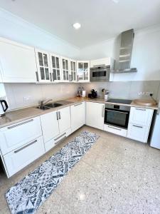 - une cuisine avec des placards blancs et un tapis au sol dans l'établissement Villa Michael, à San Pawl il-Baħar