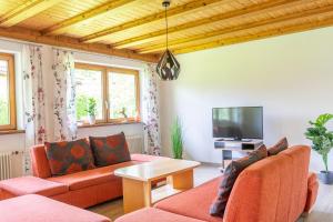 a living room with orange furniture and a flat screen tv at Haus Bergfink in Waltenhofen