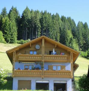 a building with a wooden roof with trees in the background at Bergbauernhof Schluder in Hermagor