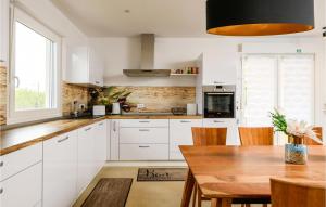 una cucina con mobili bianchi e un tavolo di legno di Amazing Home In Vodnjan With Wifi a Vodnjan (Dignano)