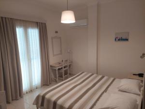 a bedroom with a bed and a table and windows at Alkyon Hotel in Kamari