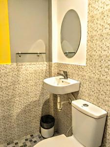 a bathroom with a sink and a toilet and a mirror at Barrio House Mactan in Mactan