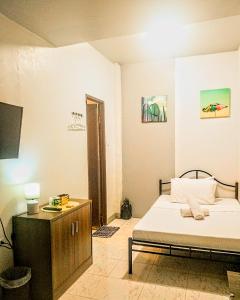 a bedroom with a bed and a cabinet and a television at Barrio House Mactan in Mactan