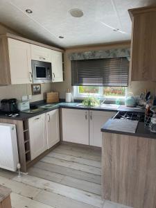 a kitchen with white cabinets and a counter top at Fern Lodge with Hot Tub in Stonham Aspall