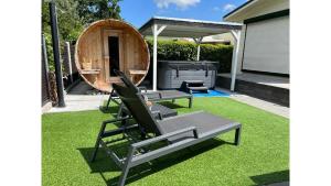 een achtertuin met 2 ligstoelen en een grill bij Chalet Buutengeweun, met luxe JACUZZI en TONSAUNA in Sint Annaland