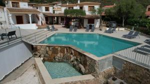 a swimming pool with a rock wall around it at Residence Chiaro di Luna in San Teodoro