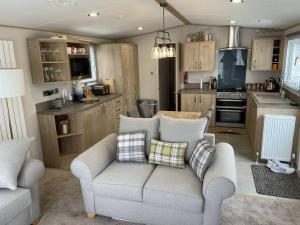 a living room with a couch and a kitchen at Mersea Villa in West Mersea