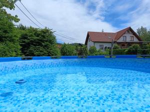 a large blue swimming pool with a house in the background at Sudecka Ostoja z Balią i Sauną in Lubawka