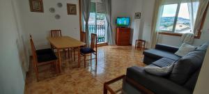 salon z kanapą i stołem w obiekcie Pisos Vistalegre 2B con jardín cerca del mar w mieście Sanxenxo