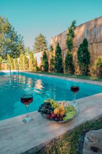 a plate of fruit and wine glasses next to a pool at Twins Bungalow in Sapanca