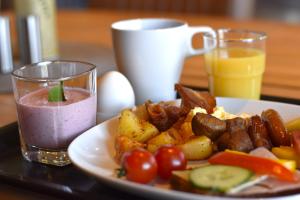 a plate of food with a pink drink and a plate of food with tomatoes at Munken Hotell & Konferens in Mönsterås