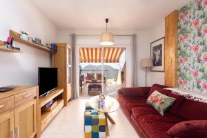 a living room with a red couch and a table at Home2Book Calma Sun Home Chayofa, Terrace & Pool in Chayofa