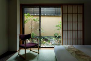 een slaapkamer met een stoel voor een raam bij Gion Misen Furumonzen in Kyoto