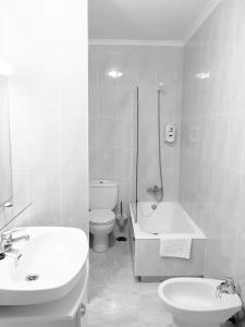 a bathroom with a sink and a toilet and a bath tub at Apartamentos Salceda in Noja