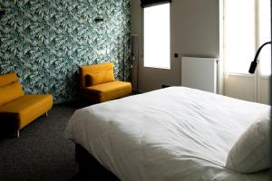 a bedroom with a white bed and a yellow chair at Hôtel de la Poste in Ellezelles