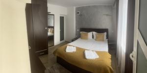 Un dormitorio con una cama con sábanas y almohadas amarillas y blancas. en Casa Anne Marie, en Sinaia