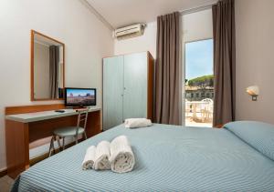 una camera d'albergo con letto, scrivania e finestra di HOTEL GIARDINO a Cesenatico