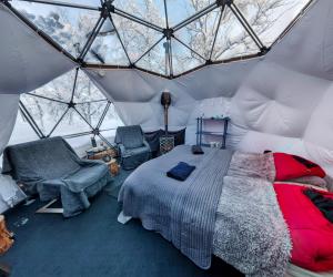 a bedroom in a dome tent with a bed and chairs at Aurora Dome in Kiruna