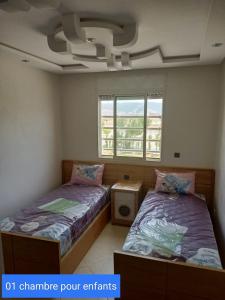 two beds in a room with two windows at CASA SANYA RMEL Tetouane in Tetouan