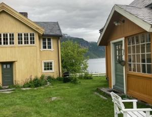 a house with a yard next to a house with a lake at Steinsvoll Gård in Vang I Valdres