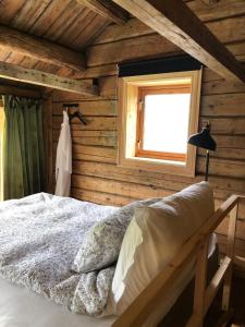 a bedroom with wooden walls and a bed with a window at Stokke Gård Burglamping in Stjoerdal