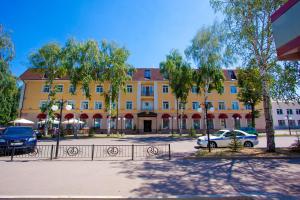 a large yellow building with cars parked in front of it at Grand Hotel Vostok in Sterlitamak