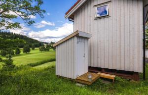 a small white building with a bench next to it at Stokke Gård Burglamping in Stjoerdal