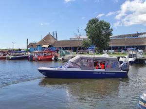 a blue boat in the water with people on it at Pensiunea Cuplu Călător in Jurilovca
