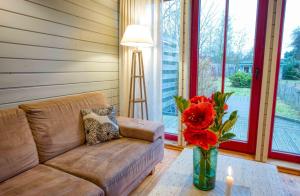 sala de estar con sofá y jarrón con flores en traumHaff - Sea Hideaway Ostsee Region - privates NORDICSPA, Kamin, Kunst, Hund 300m zum Strand, en Rieth