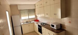 una pequeña cocina con armarios blancos y microondas en CA LAU, en Burriana