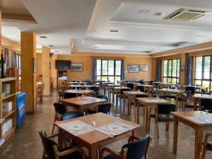 a restaurant with wooden tables and chairs and windows at Hotel Restaurante La Cañada in Fuencaliente de Lucio