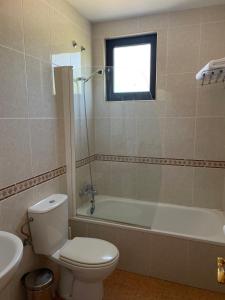 a bathroom with a toilet and a tub and a sink at Hotel Restaurante La Cañada in Fuencaliente de Lucio