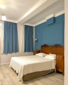 um quarto com uma cama grande e paredes azuis em Promenade Hotel em Shkodër