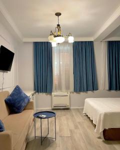 a bedroom with a bed and a couch and blue curtains at Promenade Hotel in Shkodër